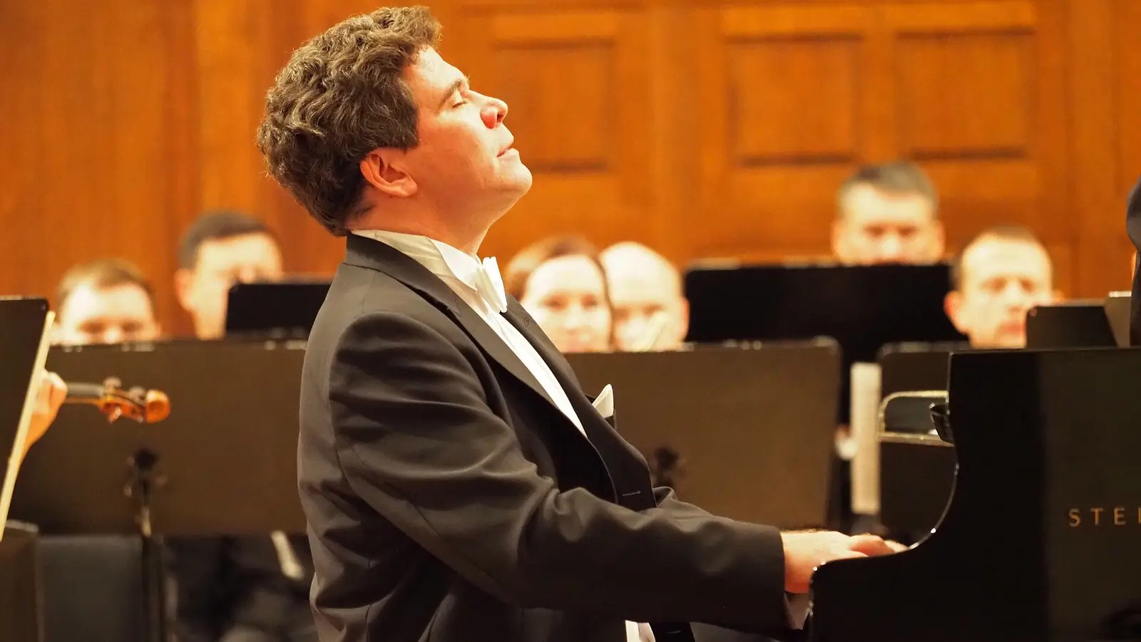 Denis Matsuev at the piano with his head raised, playing with an orchestra in Kazan