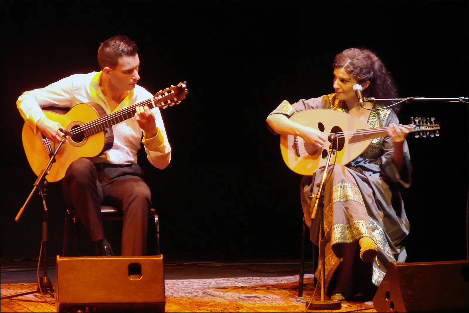 A guitarist and an oud player performing together on stage