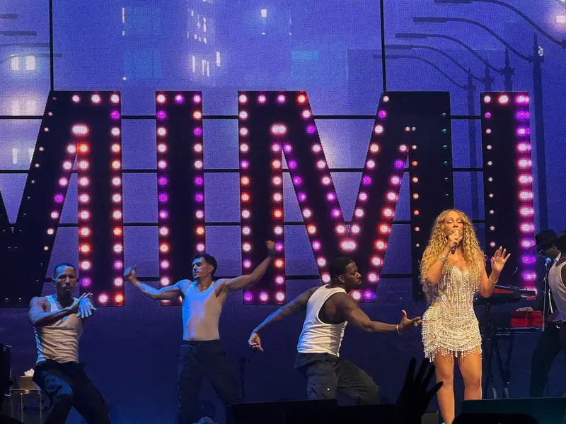 Mariah Carey performing on stage in front of large illuminated letters at Mall of Asia Arena
