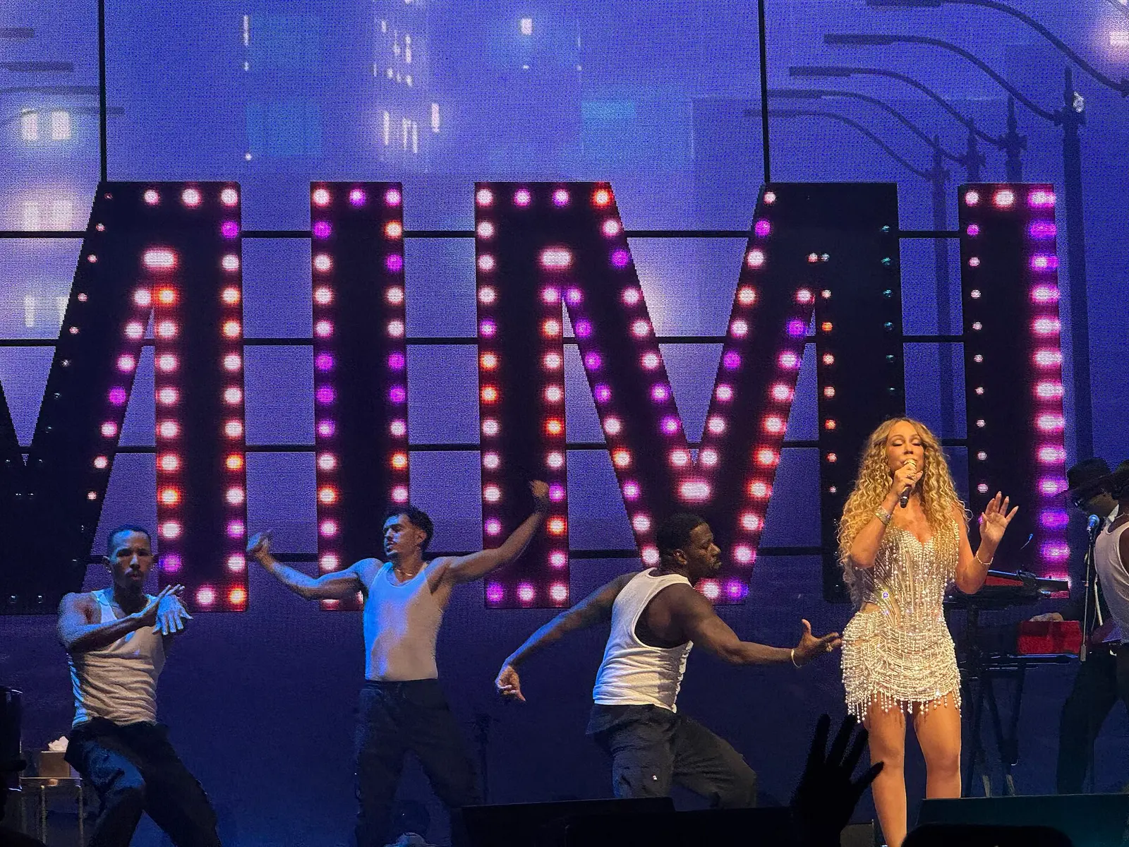 Mariah Carey performing on stage in front of large illuminated letters at Mall of Asia Arena