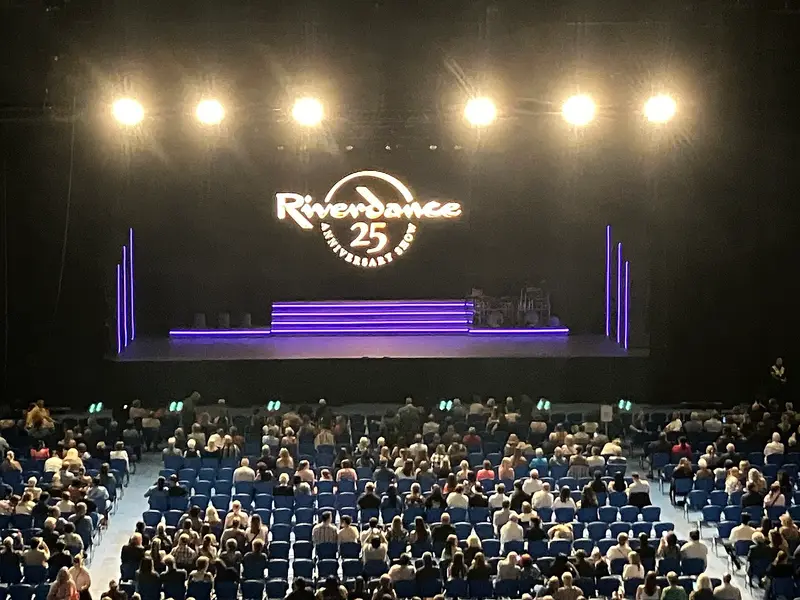 The Riverdance 25th anniversary stage lit in an arena before a seated audience