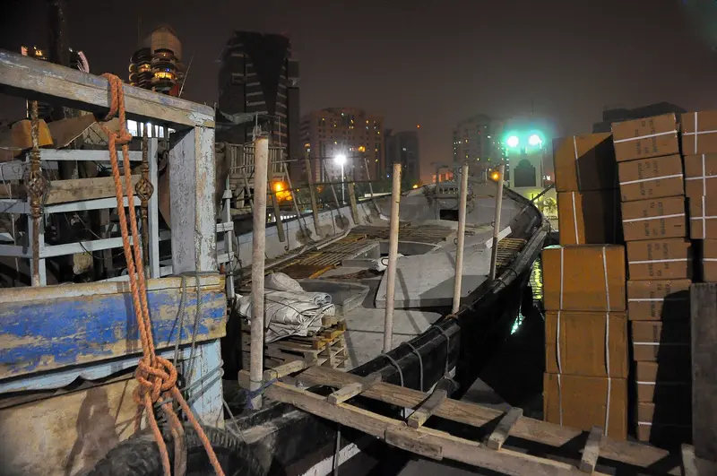 A wooden trading dhow being loaded at night on Dubai Creek
