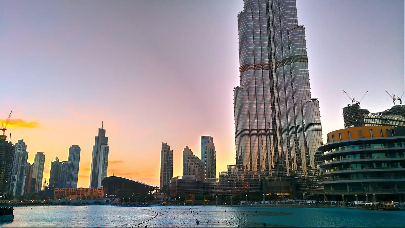 Burj Khalifa rising above the Dubai Fountain lake at dusk