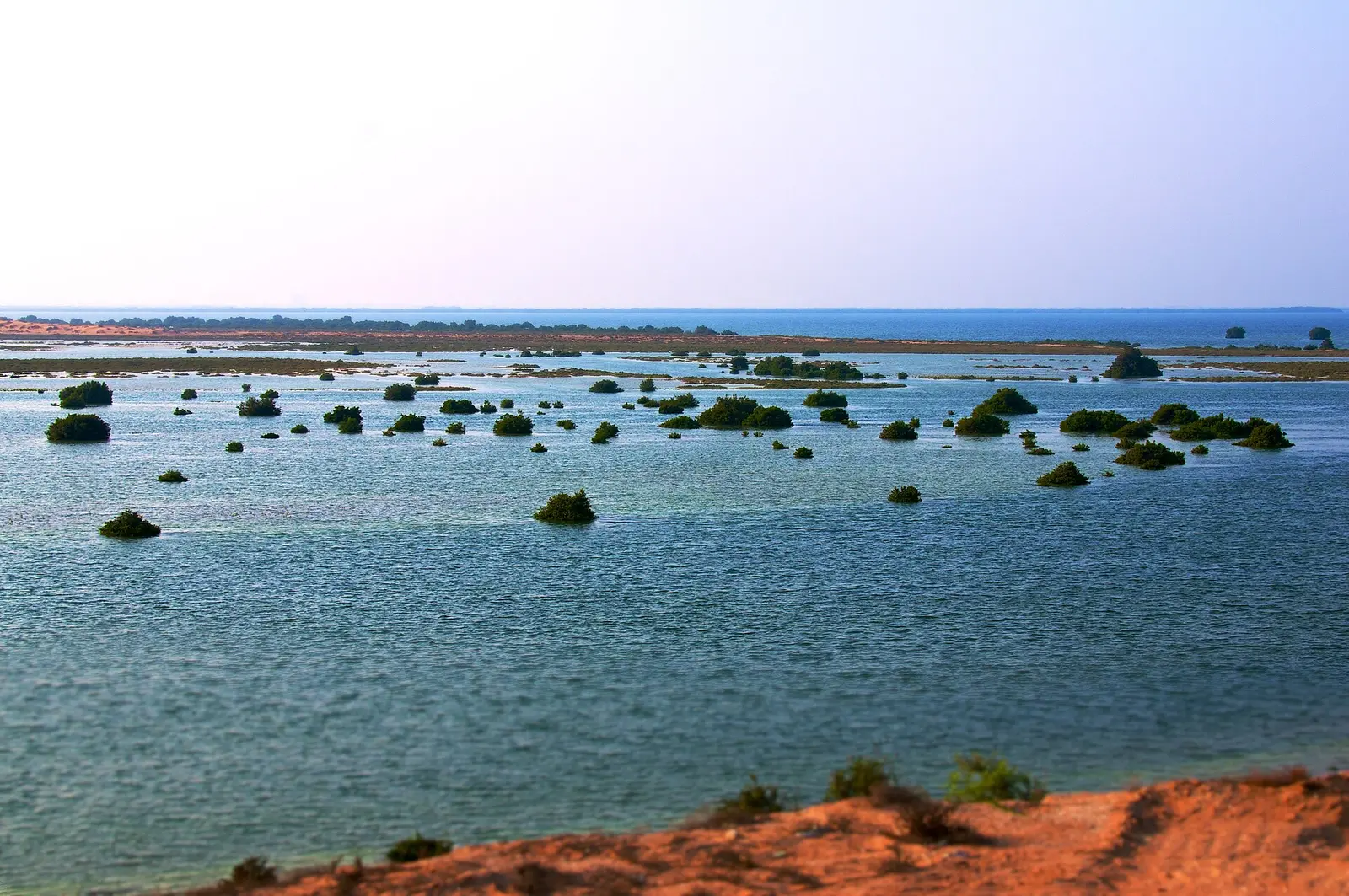 Shallow turquoise water and low rocky islets along the coast at Umm Al Quwain