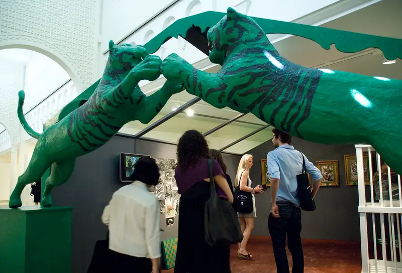 Visitors looking at a green tiger sculpture installation at the Sharjah Biennial
