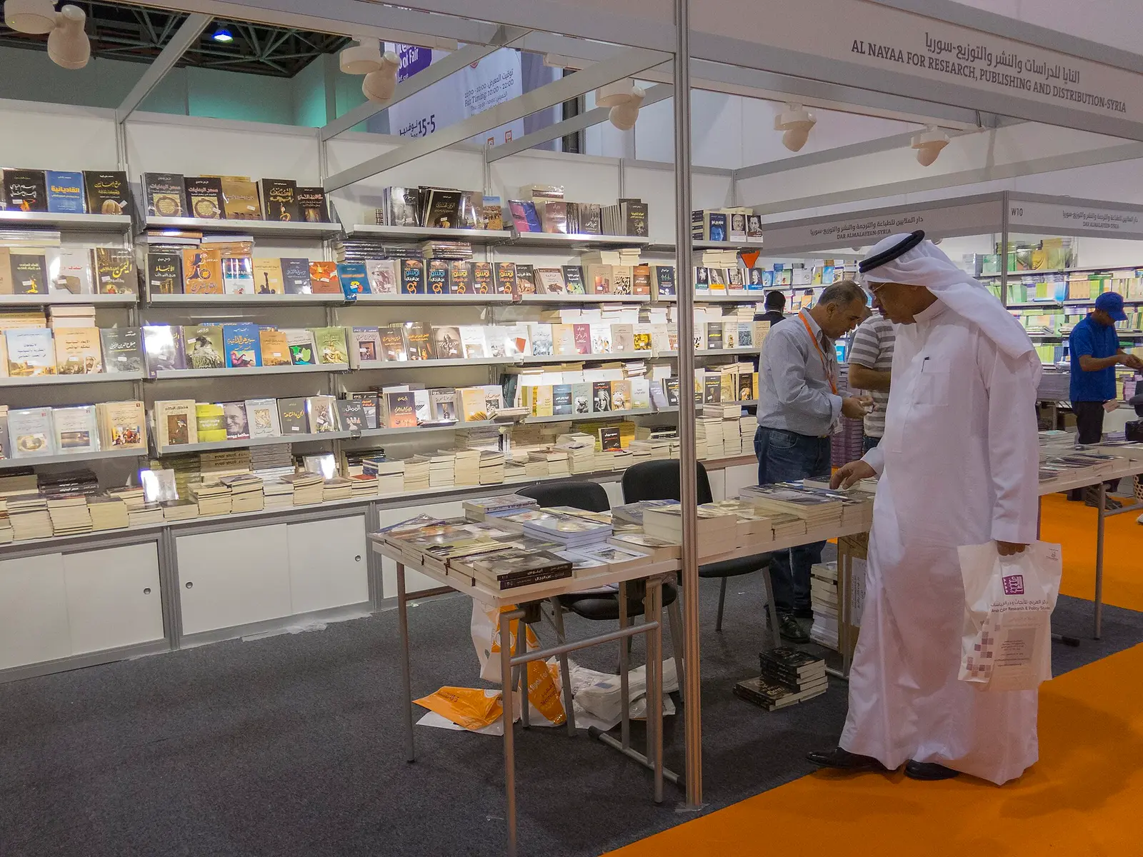 Visitors browsing shelves of books on a stand inside an exhibition hall at Expo Centre Sharjah in 2014